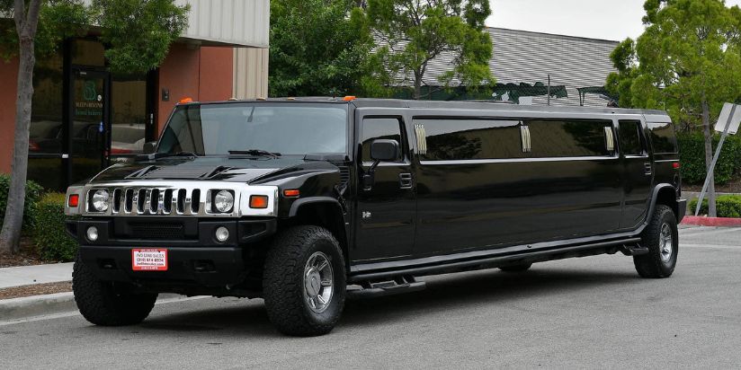 The hummer limo is parked next to a beautiful house