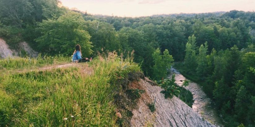 girl sitting on a cliff in rogue national urban park Ontario