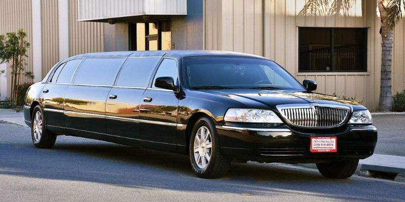 The sedan limo is parked to a beautiful house
