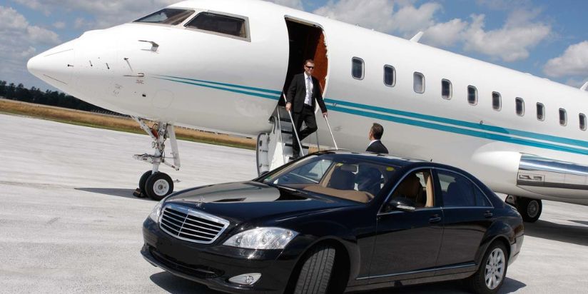 a person coming out of small plane and hired airport limo car with chauffeur is there to receive him